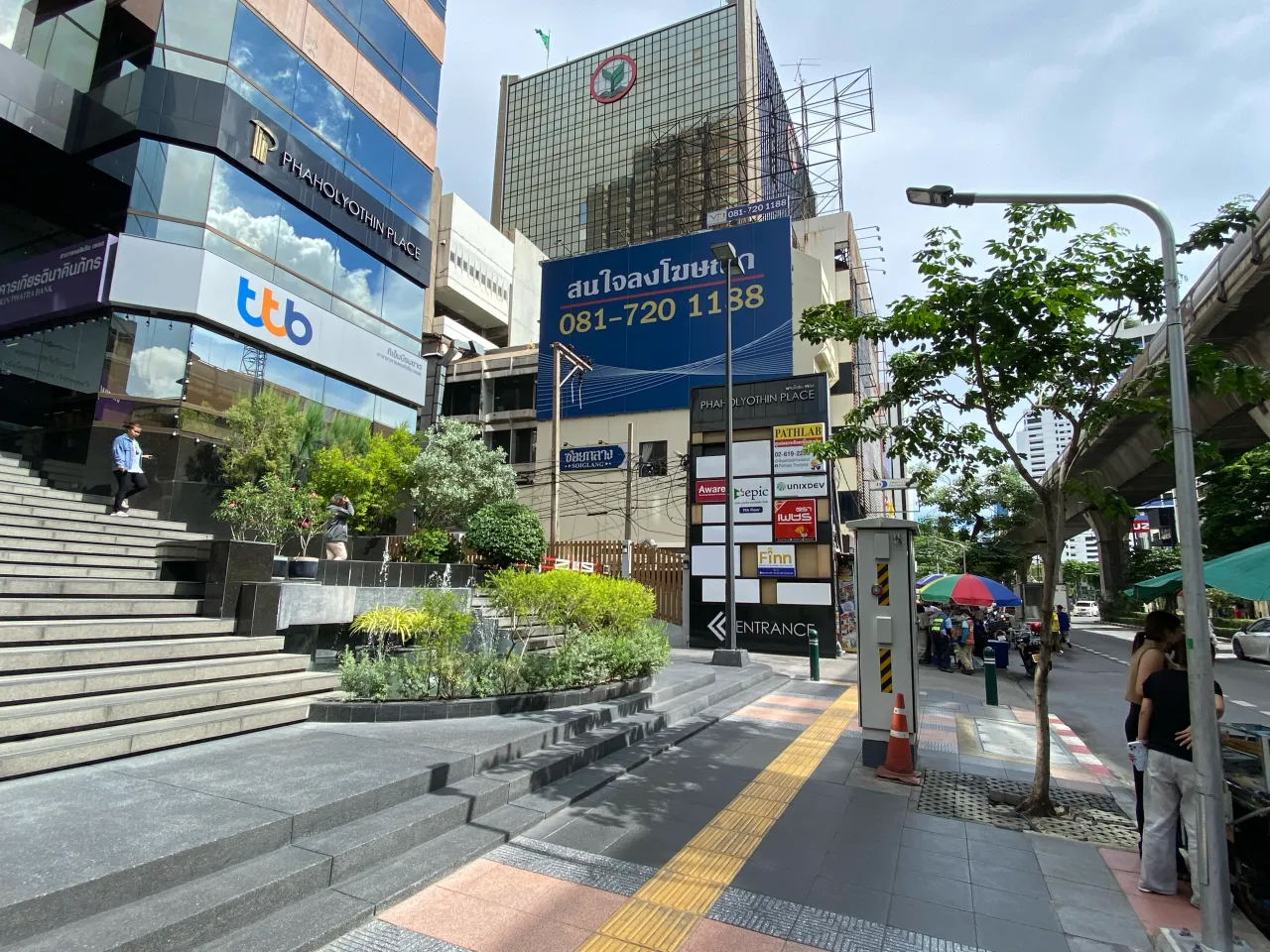 Phaholyothin Place frontage — the ENTRANCE sign, with parking just past the front
